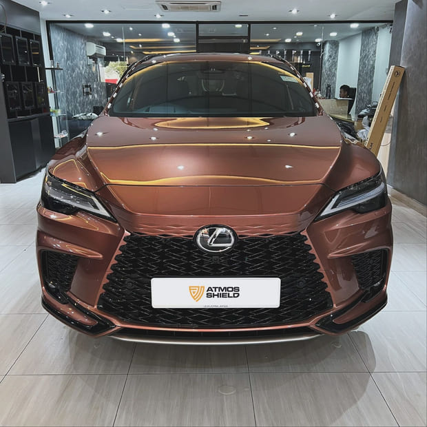 A Lexus RX350 head-on in a tiled interior bay, its bodywork a bronzed copper.